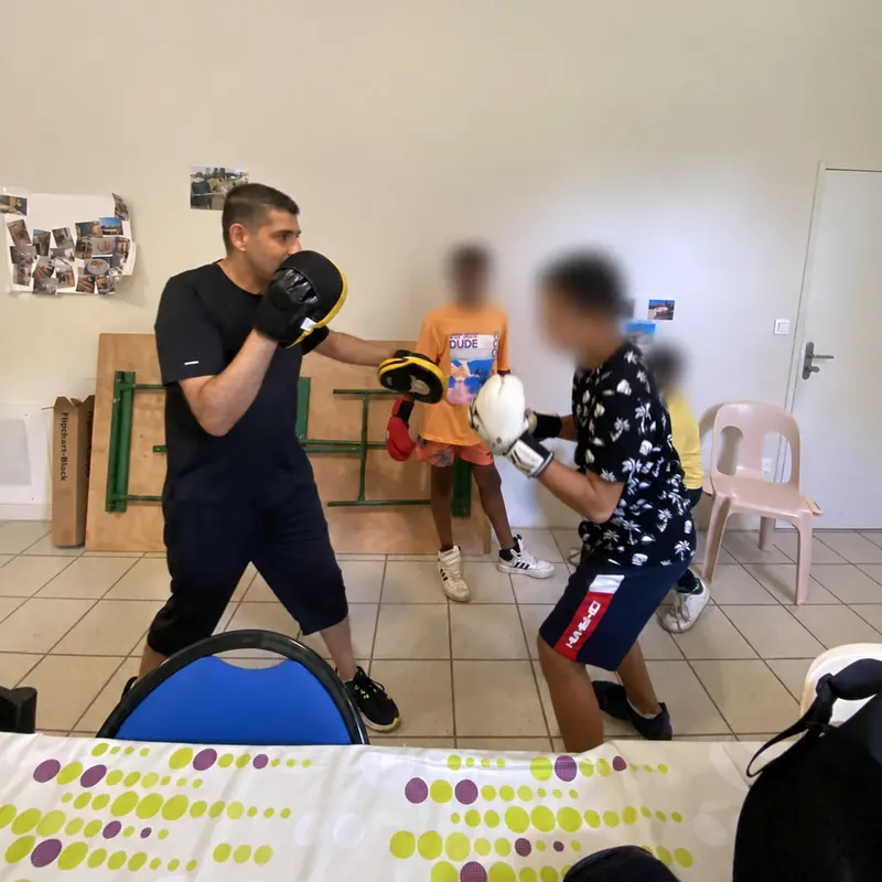 Kamel guide un exercice de boxe ; les visages des participants sont floutés