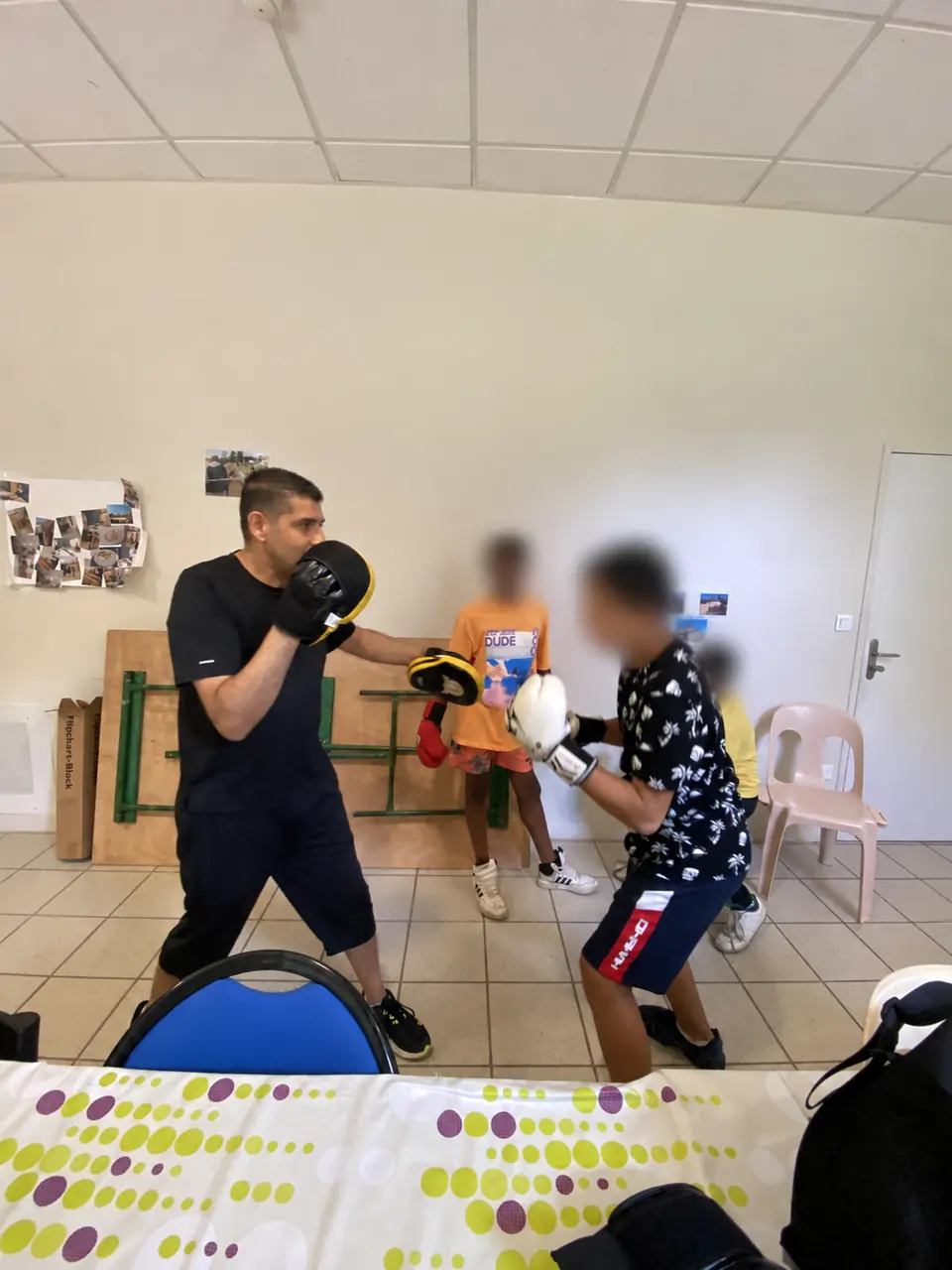 Kamel guide un exercice de boxe ; les visages des participants sont floutés